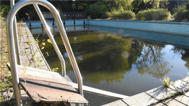 Heeslingen plant: Neues Wasserspielerlebnis statt Freibad Ein blau gekacheltes Becken, in dem Wasser steht und im Vordergrund ist ein glänzender Metallbogen.