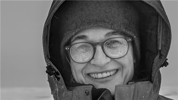 Eine Frau lächelt auf diesem Schwarzweißfoto in die Kamera. 
