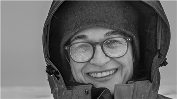 Eine Frau lächelt auf diesem Schwarzweißfoto in die Kamera. 