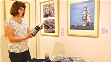 Dr. Kerstin Ras-Dürschner hat an der Ausstellung gearbeitet. Die Sektflasche, die sie in der Hand hält, wurde anlässlich der ersten Sail angeboten.
