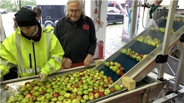 Dr. Wolfgang Meiners (rechts), Leiter der Umweltstation, freut sich über das Förderband, das die Apfelsaftherstellung erheblich erleichtert.
