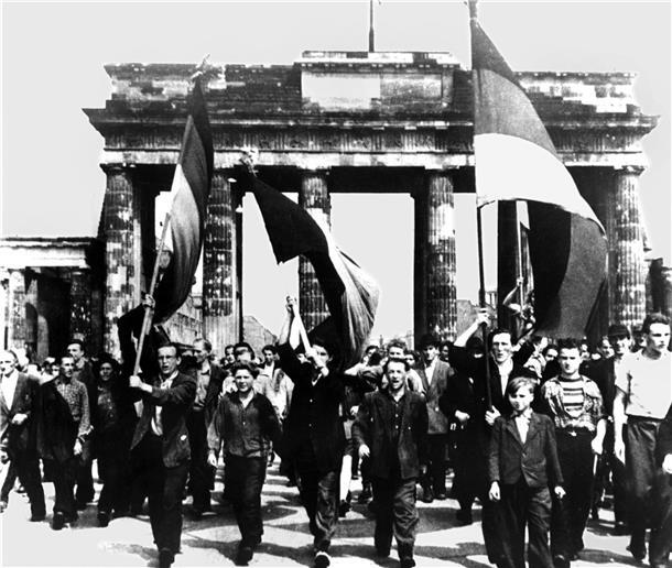 Ost-Berliner marschieren mit wehenden Fahnen vom Ost-Sektor aus durch das Brandenburger Tor. Am 17. Juni 1953 protestierten in der DDR eine Million Menschen gegen den noch jungen sozialistischen Staat - bis sowjetische Panzer den Aufstand beendeten. 
