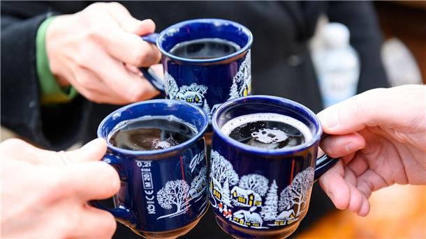 Drei Besucher stoßen in Hamburg mit Glühwein an.