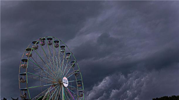 Dunkle Regenwolken ziehen über ein Riesenrad auf dem Gelände des Hurricane-Festivals in Scheeßel hinweg.