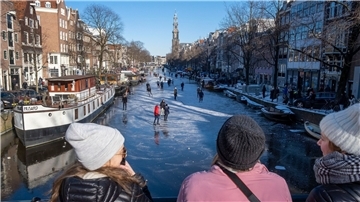 Dutzende von Schlittschuhläufern laufen auf der gefrorenen Oberfläche von Amsterdams historischem Prinsengracht-Kanal.
