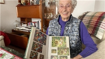 Eine alte Frau mit einem Album mit Tauschbildern.