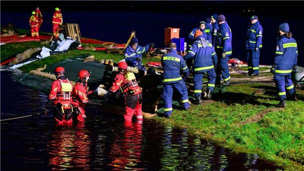 Ehrenamtliche Einsatzkräfte vom THW und der DLRG befestigen einen Deich in Niedersachsen.