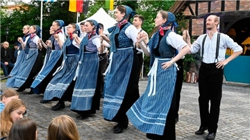 Frauen mit blauen Schürzen stehen nebeneinander.