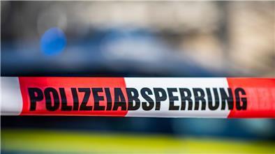 Ein Absperrband mit der Aufschrift „Polizeiabsperrung“ ist vor einem Polizeiwagen aufgespannt.