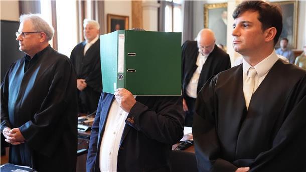 Prozess um teuren Schrott - Anwalt beklagt Unterstellungen Ein Angeklagter verdeckt im Hamburger Landgericht sein Gesicht mit einem Ordner. Zwei Lieferanten und ein Materialprüfer sollen den Hamburger Kupferhersteller Aurubis um Millionen betrogen haben.