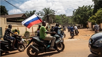 London: Wagner-Armee wird wieder aktiver Ein Anhänger von Hauptmann Traore schwenkt eine russische Fahne auf einem Motorrad.
