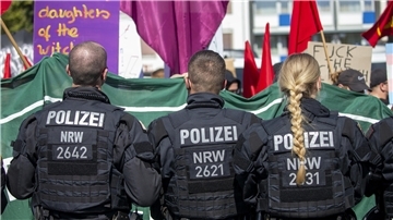 Drei Polizeibeamte von hinten bei einer Demonstration