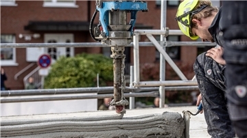 Ein Arbeiter inspiziert die Baustelle eines Mehrfamilienhauses aus dem 3D-Drucker.