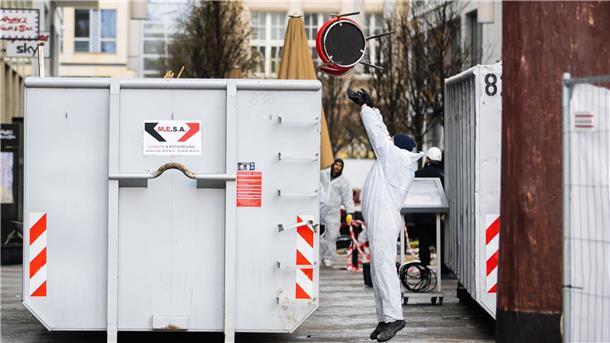 Ein Arbeiter wirft einen Stuhl in einen Container.