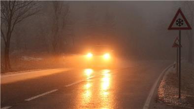Verkehrsunfälle wegen Schnee und Glätte in Niedersachsen Ein Auto fährt bei Glatteis und Nebel über eine Straße.