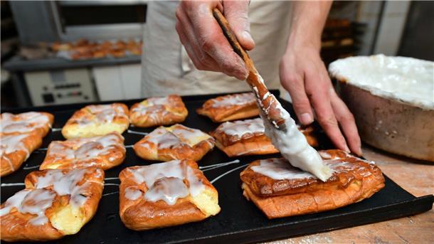 Nachfolgermangel gefährdet Tausende mittelständische Firmen Ein Bäckermeister pinselt Zuckerguss auf süßes Gebäck in seiner Backstube.