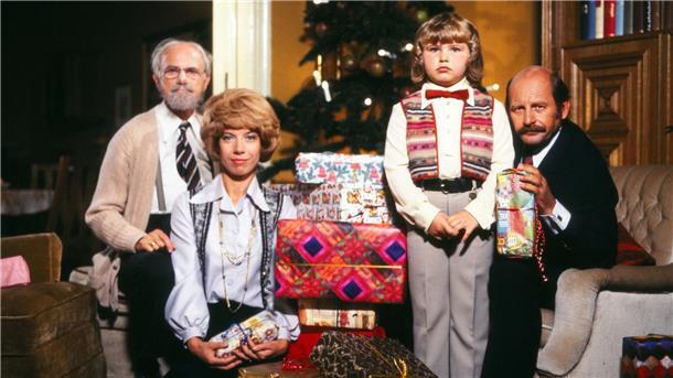 Eine Familie sitzt gemeinsam vor einem Tannenbaum.