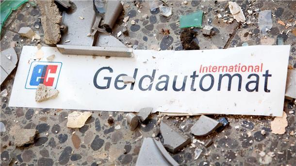Das Schild eines Geldautomaten liegt zwischen Scherben und Trümmern auf dem Boden.
