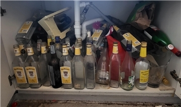 Mehrere leere Glasflaschen in einem Unterbauschrank einer Spüle.
