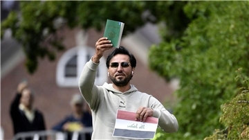 Ein Demonstrant hält eine Kopie des Korans hoch, die er mutmaßlich gemeinsam mit einer irakischen Fahne verbrennen will.