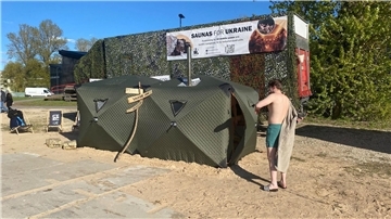 Ein Festival-Besucher steht vor einer mobilen Front-Sauna, die in Estland für die ukrainische Armee entwickelt worden ist.