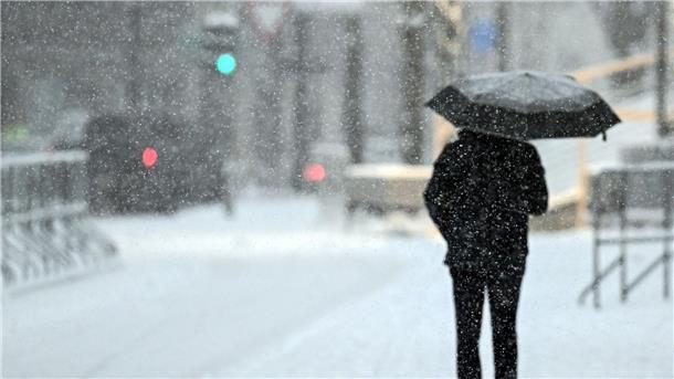 Winterwetter bremst Verkehr in Teilen Deutschlands aus Ein Fußgänger geht mit einem Schirm durch das Schneetreiben in Köln.