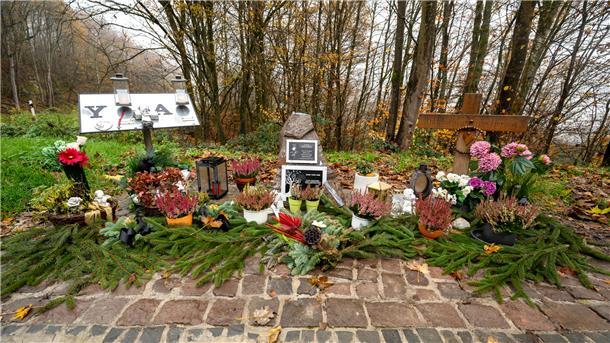 Ein Gedenkstein und Blumen sind in der Nähe des Tatorts an der K22 bei Kusel aufgestellt, wo Ende Januar 2022 zwei Polizisten im Dienst getötet wurden. 