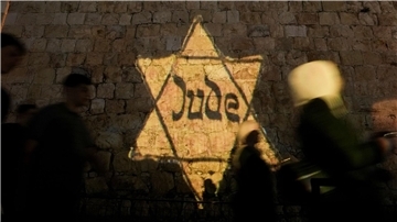 Ein gelber Davidstern mit der Aufschrift „Jude“, ähnlich dem, den Juden in Nazi-Deutschland tragen mussten, wird am Abend des jährlichen Holocaust-Gedenktages Yom HaShoah auf die Mauern der Jerusalemer Altstadt projiziert.