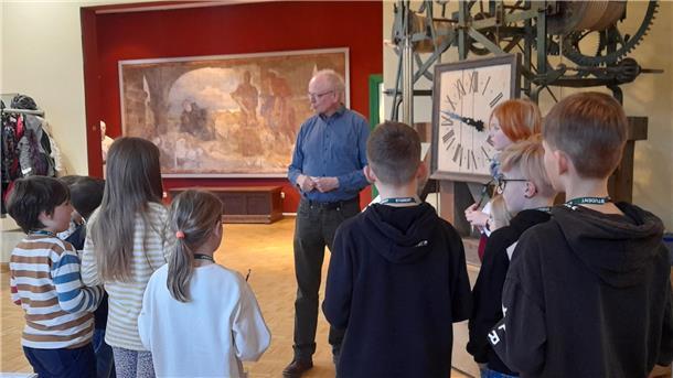 Ein Mann erklärt Kindern im Museum Nordenham, wie die dort ausgestellte Kirchturmuhr funktioniert.