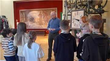 Ein Mann erklärt Kindern im Museum Nordenham, wie die dort ausgestellte Kirchturmuhr funktioniert.