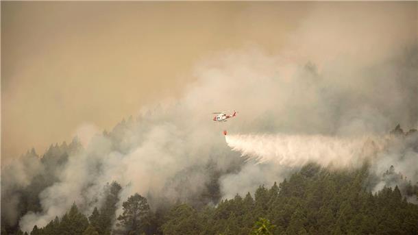 Waldbrand auf Teneriffa zwingt zu weiteren Evakuierungen Ein Hubschrauber überfliegt einen Brand am Stadtrand von El Rosario während eines Löscheinsatzes.