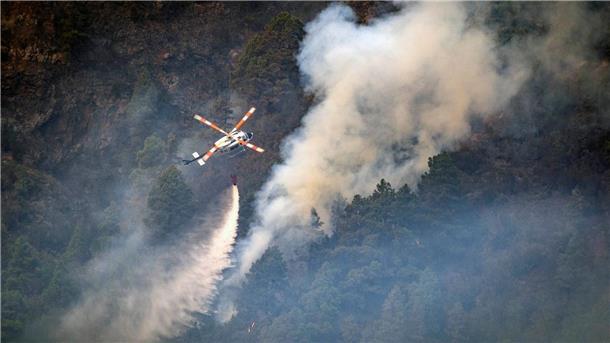 Waldbrand auf Teneriffa erfasst bereits 11.600 Hektar Ein Hubschrauber wirft Wasser auf die Flammen, während sich das Feuer durch den Wald in Richtung der Stadt Pinolere ausbreitet.