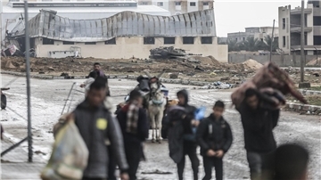 Ein israelischer Panzer ist zu sehen, während Palästinenser das Nasser-Krankenhaus und die angrenzenden Schulen verlassen.