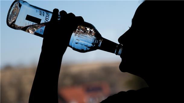 Ein jugendliches Mädchen trinkt in ihrem Zimmer eine Flasche Wodka. 