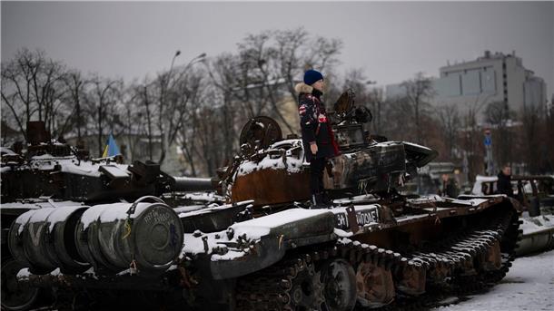 Ein Junge steht auf einem zerstörten russischen Panzer in der Kiewer Innenstadt.