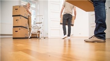 Ein junger Mann, eine ältere Frau und ein älterer Mann tragen Umzugskartons in eine Wohnung. In Deutschland betrug das Durchschnittsalter beim Auszug geschlechterübergreifend 23,8 Jahre.