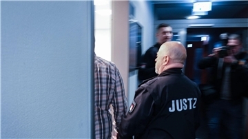 Ein Justizbeamter begleitet den Angeklagten in den Gerichtssaal.