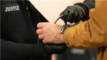 Ein Justizbeamter schließt einem Angeklagten im Gerichtssaal Handschellen auf.