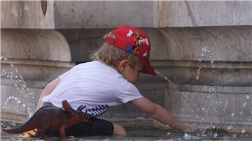 Ein Kind kühlt sich bei 38 Grad Celsius an einem Brunnen ab.