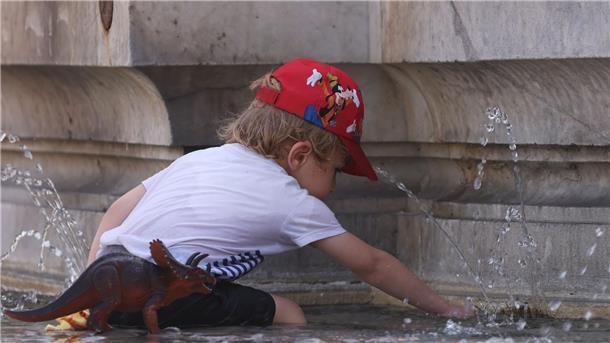 Bundesamt: Mehr Schattenplätze an Kitas und Schulen Ein Kind kühlt sich bei 38 Grad Celsius an einem Brunnen ab.