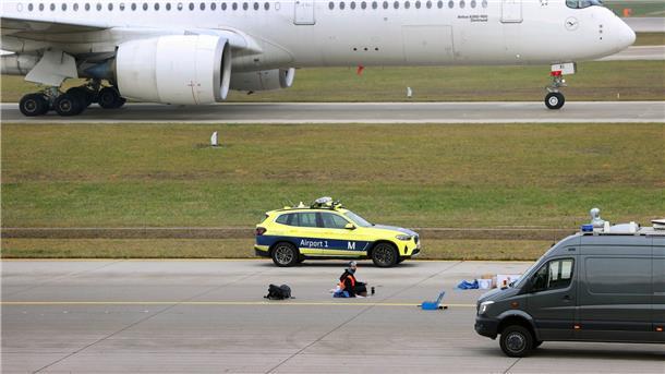 Ein Klimaaktivist sitzt mit angeklebter Hand auf dem Start-und Landebahn am Airport Franz-Josef-Strauß in München.