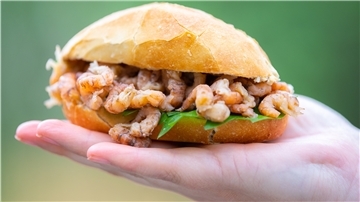 Ein Krabbenbrötchen liegt in einer Hand.