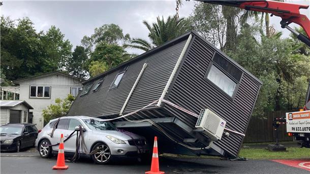 Ein Kran hebt ein Tiny-House von einem Auto nach massiven Regenfällen in Auckland.