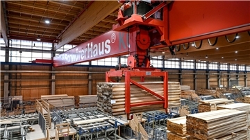 Ein Kran hebt eine Ladung Holz an, um diese in einer Halle der SchwörerHaus KG zu einem anderen Platz zu transportieren.