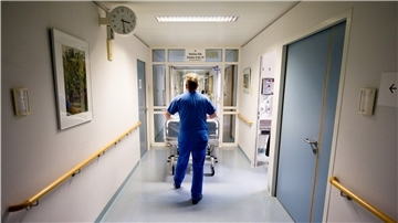 Ein Krankenpfleger schiebt in einer Klinik ein Krankenbett durch den Flur. Pflegekräfte leiden derzeit unter Personalmangel in ihren Einrichtungen.