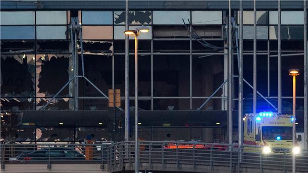 Ein Krankenwagen fährt an der zerstörten Fassade des Terminals des Flughafens Zaventem. (Archivbild)
