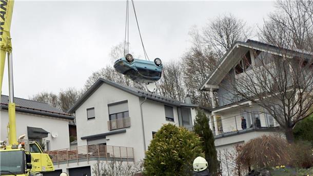 Ein Kranwagen hebt den verunglückten Kleinwagen von der Terrasse und dem Garten eines Einfamilienhauses in Gummertsbach.