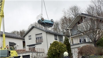 Ein Kranwagen hebt den verunglückten Kleinwagen von der Terrasse und dem Garten eines Einfamilienhauses in Gummertsbach.