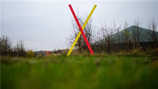Ein Kreuz steht als Protest gegen eine geplante Neubaustrecke der Bahn an einem Hof. (Archivbild)