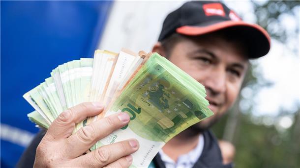 Streikende Fahrer hoffen auf Geld und Dominoeffekt Ein Lkw-Fahrer mit einem Bündel Geldscheinen in der Hand.